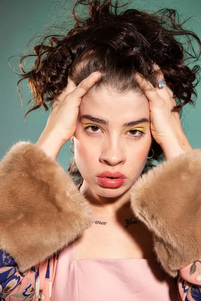 Yüzüne yakın eli olan genç Avrupalı kadın yeşilde izole edilmiş.