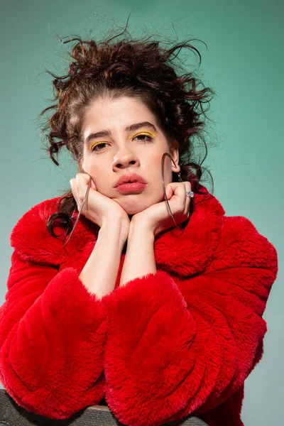 Kırmızı portredeki kıvırcık saçlı kız yeşile izole edilmiş.