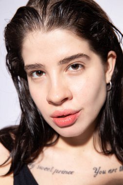 Hafif gülümseyen beyaz, siyah saçlı kız portresi.