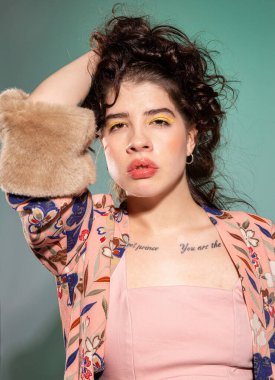 Yüzüne yakın eli olan Avrupalı genç bir kadın. Yeşil üzerinde izole edilmiş koca dudaklar.