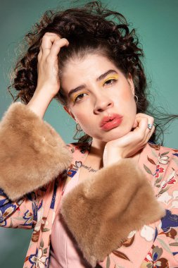 Yüzüne yakın eli olan genç Avrupalı kadın yeşilde izole edilmiş.