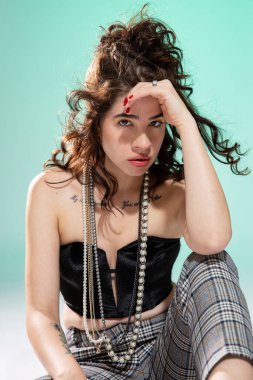 Kız elini yeşilde izole edilmiş yüzüne yakın bir şekilde yerde oturuyor.