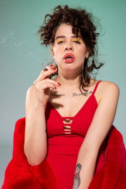 Kırmızılı beyaz kız mankeni ve yeşil sigara izole edilmiş.