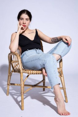 Açık mavi üzerinde tek başına oturan genç kadın.