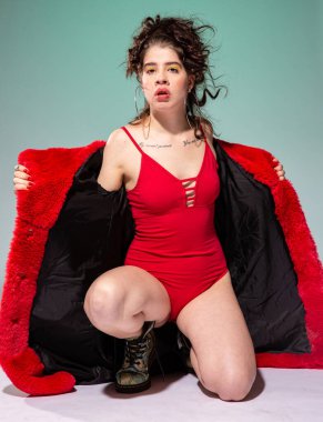 Kırmızılı beyaz manken yeşil mayo içinde yalnız oturuyor.