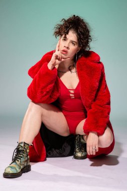 Kırmızılı beyaz manken yeşilde tek başına oturuyor.