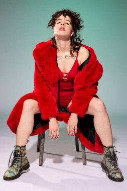 Kırmızılı beyaz Avrupalı kız, koca dudaklı yeşil üzerinde tek başına oturuyor.