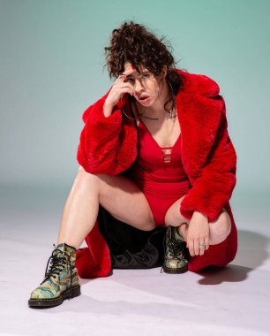 Kırmızılı beyaz manken, yeşilde izole edilmiş yüzünün yanında oturuyor.