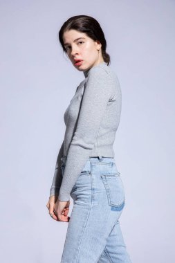 Gri kazaklı beyaz kız Gri üzerine izole edilmiş