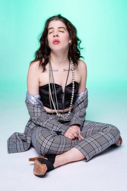 Yerde oturan koyu renk saçlı kız yeşil üzerine izole edilmiş.