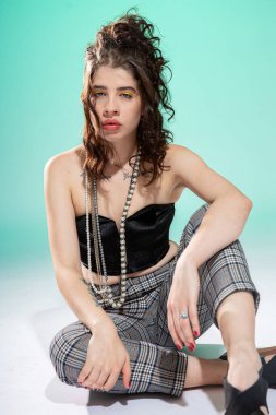 Kız yeşil dudaklı, kocaman dudaklarıyla yerde oturuyor.