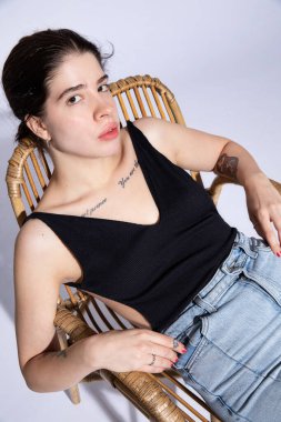 Siyah bluzlu beyaz bir kadın. Büyük dudakları var. Açık mavi renkte.