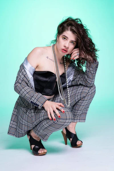 Koyu saçlı, çömelmiş kız yeşil üzerine izole edilmiş.