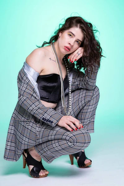 Koyu saçlı, çömelmiş genç bir kız. Yüzüne yakın, yeşil bir yerde.