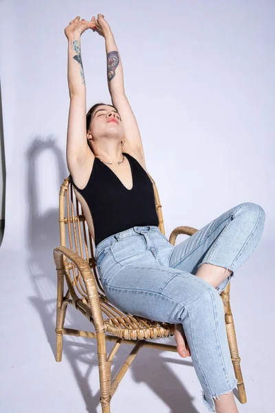 Gri renkte elleri havada oturan genç kız.