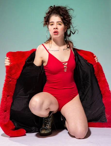 Kırmızılı beyaz manken yeşil mayo içinde yalnız oturuyor.