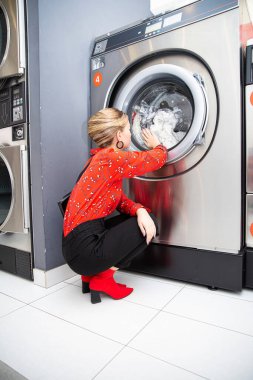 Kırmızı etekli manken ellerini çamaşır makinesinin arkasına koy.