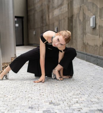 Siyah elbiseli kadın kaldırım taşlarının üzerinde oturuyor.