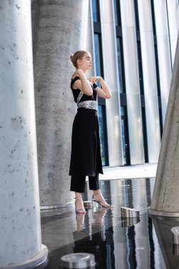 Genç beyaz model kız. Yüzüne yakın duruyor. Şehir binası geçmişi var.