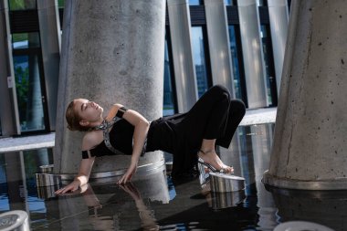 Beton sütunların arasında yere değen genç bir model kız.