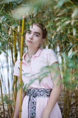 Ağaçların arkasında duran beyaz genç kadın.