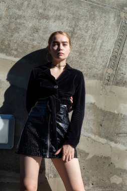 Kahverengi taş arka planda duran siyah elbiseli genç kız.