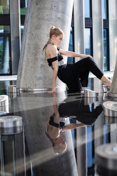 Genç beyaz model kız, şehir binası geçmişiyle yerde oturuyor.