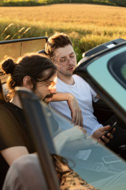 Genç çocuklar arabada gözlüklü mankenler.