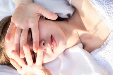 Beyaz kadın modeli yüzünü elleriyle koruyor.