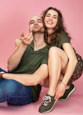 Mutlu genç çift pembe üzerine izole edilmiş gülümsüyor.