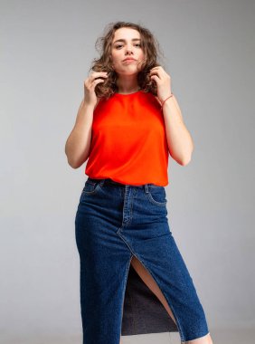 Gri ve kırmızı bluzlu, etekli beyaz kadın.