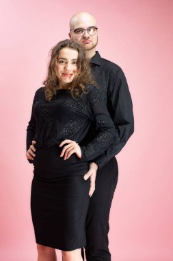 Genç bir kadın ve bir adam pembe üzerinde yalnız duruyor.