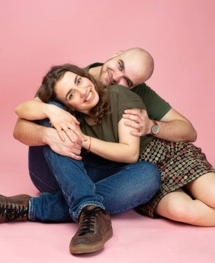 Mutlu beyaz çift pembe üzerinde yalnız oturuyor.