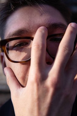 Beyaz Avrupalı genç adam yakın plan portresi yüzünü elleriyle kapattı.