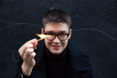 Gülümseyen Avrupalı genç beyaz adam ve siyah bir kibrit.