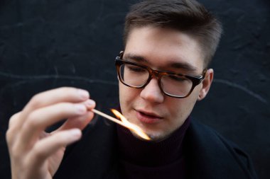 Yanan kibritle siyah üzerine izole Avrupalı genç beyaz adam portresi