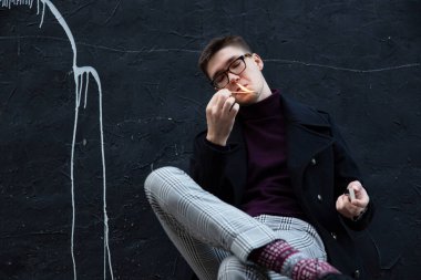 Avrupalı genç beyaz adam, siyahların üzerine oturmuş ateşle oynuyor.