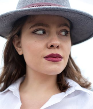 Beyaz, ciddi, gri şapkalı, beyaz tenli bir kadın.