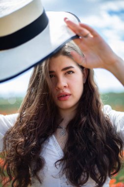 Arkasında gökyüzü olan Avrupalı genç kız hasır şapka takıyor
