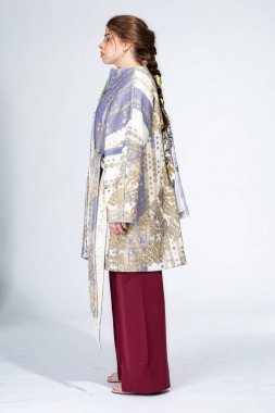 Avrupalı genç bir kadın açık gri üzerinde, kışlık ceketiyle duruyor.