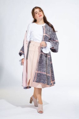 Dolgun dudaklı genç beyaz kız açık gri üzerinde tek başına duruyor.