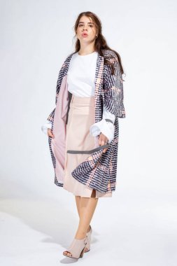 Dolgun dudaklı genç beyaz kız açık gri üzerinde tek başına duruyor.