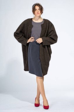 Açık gri etekli, büyük montlu, beyaz bir kız.