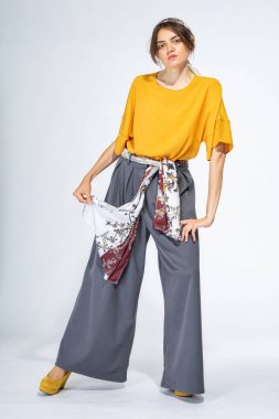 Açık gri üzerinde sarı bluz giyen genç Avrupalı kadın.