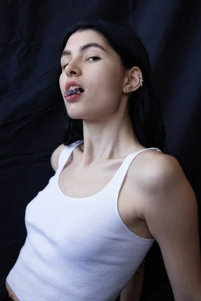 Woman with dark hair isolated on black with ice in her lips