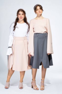 Çiçekli elbiseli genç beyaz kızlar açık gri renkte izole edilmiş.