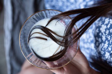 Bardakta beyaz sıvıyla siyah saçlı bir kız.