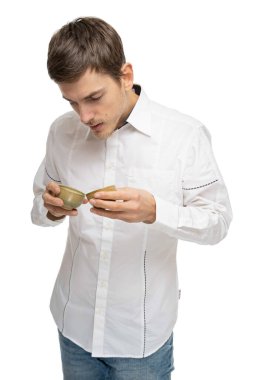 Genç yakışıklı, uzun, zayıf, kahverengi saçlı beyaz adam beyaz arka planda izole edilmiş iki çay fincanına bakıyor.