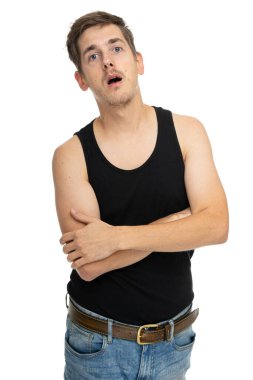 Genç yakışıklı, uzun boylu, zayıf, beyaz, kahverengi saçlı, beyaz arka planda siyah fanilalı, afallamış bir adam.