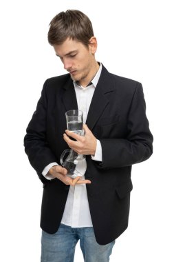 Genç yakışıklı, uzun boylu, zayıf, kahverengi saçlı, cam sürahi su ve beyaz arka planda izole edilmiş bir bardak su.